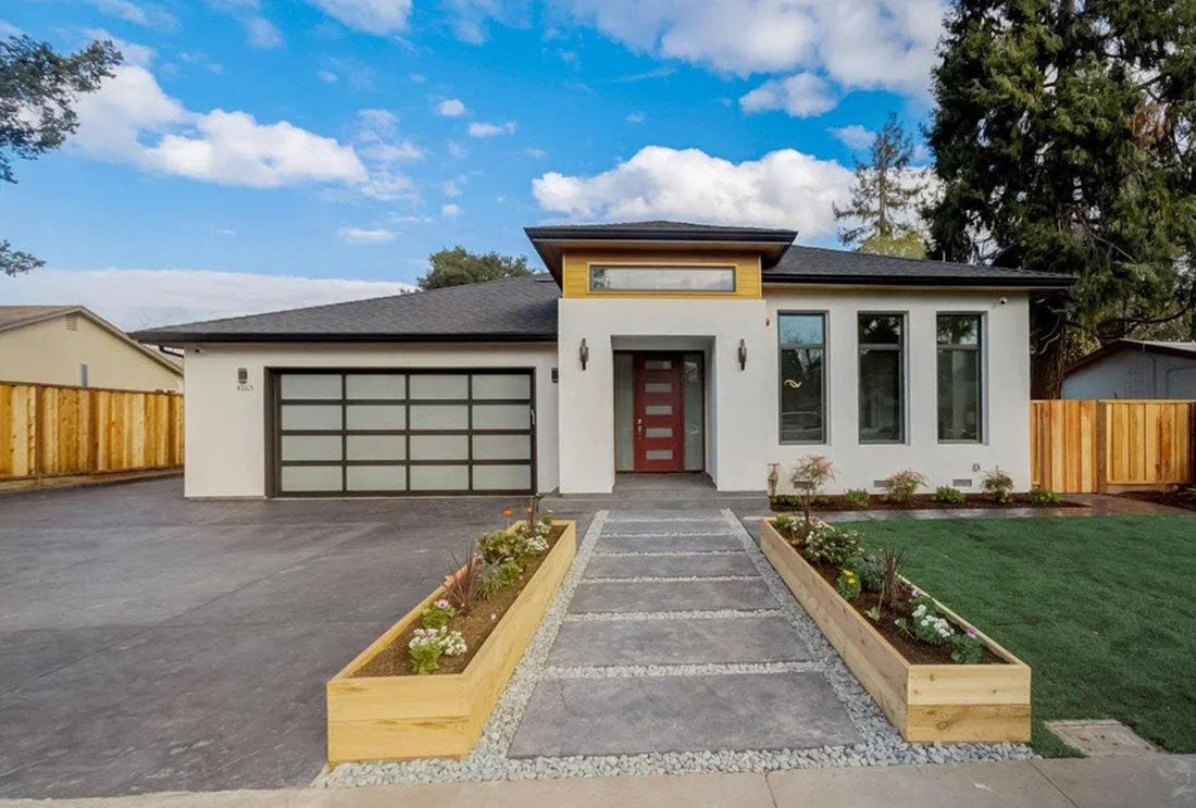 A modern single-story house with a white exterior, a red front door, and a frosted glass garage door